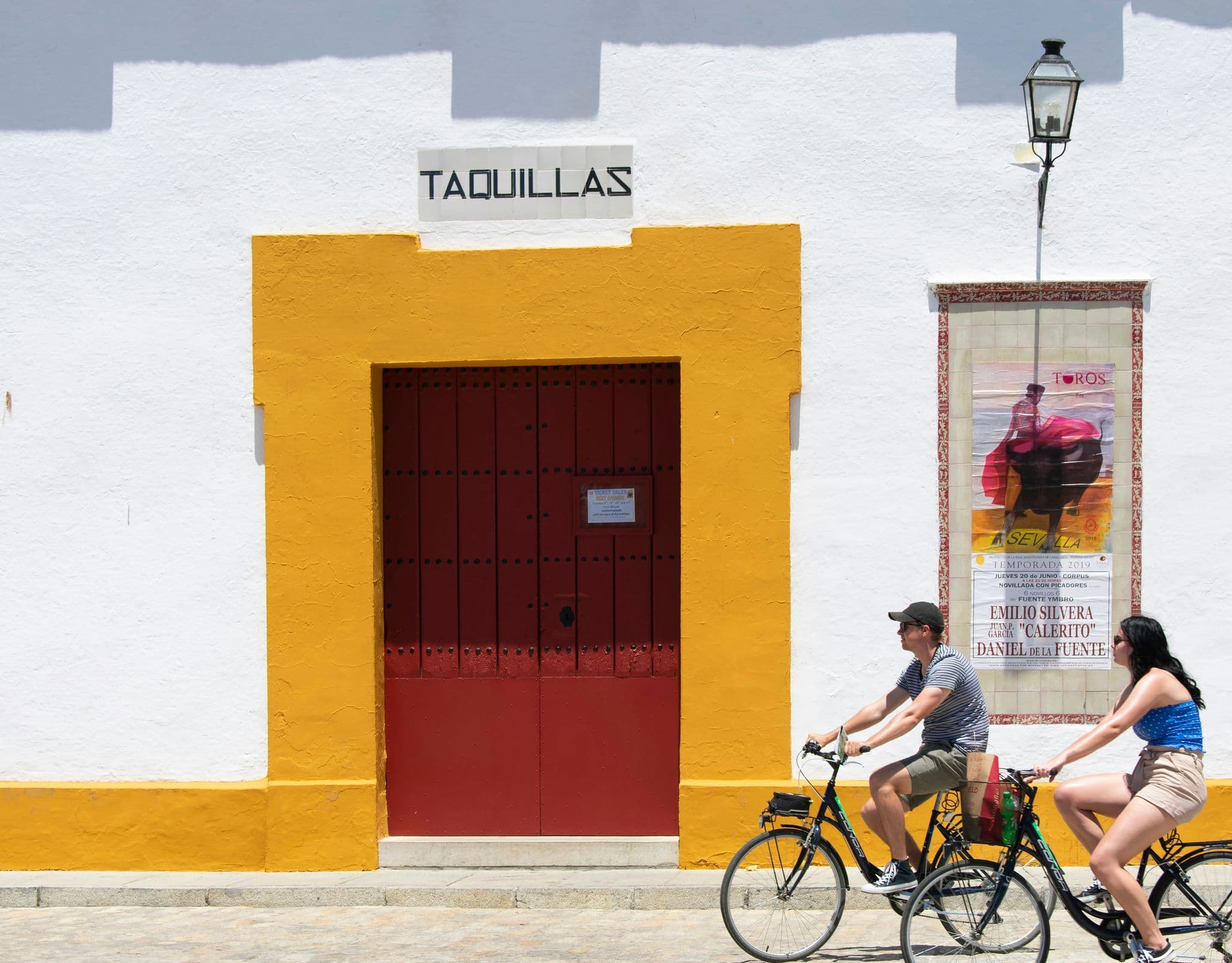 man in blue shirt riding on bicycle near red and white concrete building during daytime